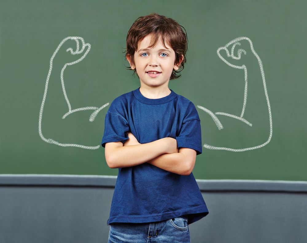 Strong child with muscles drawn on chalkboard in elementary school from Shutterstock